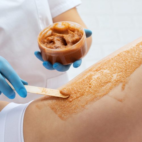 The beautician makes a cosmetic peeling procedure on the thighs of a woman. Spa procedures in a beauty salon.